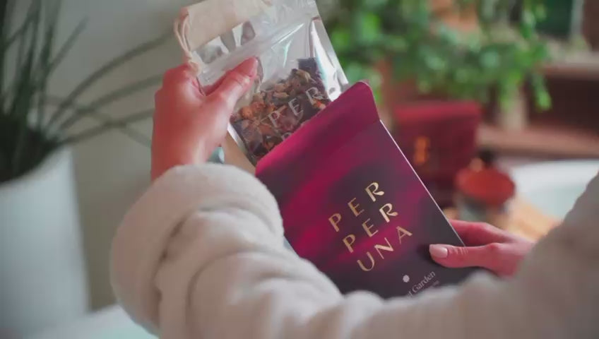 Žena pripravuje čaj do kúpeľa v bavlnenom vrecku, privoniava k nemu a relaxuje vo vani pri sviečke